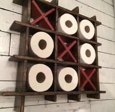 a wooden rack with several rolls of toilet paper in it and two red crosses on the top