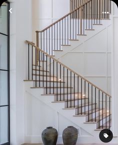 two vases sitting on the floor in front of a stair case next to a set of stairs