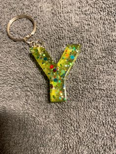 a keychain that has the letter y painted on it and is laying on a gray surface