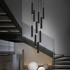 a modern chandelier hanging from the ceiling in a room with stairs and vases