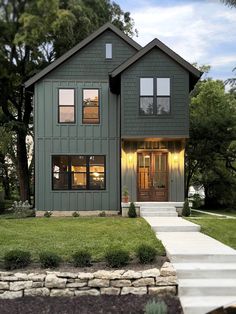 a green house with two windows and steps leading up to the front door that lead into the yard