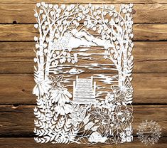 a paper cut out of flowers and trees on a wooden background with text that reads, the