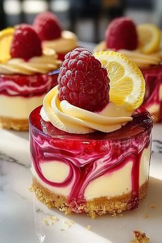 three desserts with raspberry sauce and lemon slices on top are sitting on a table