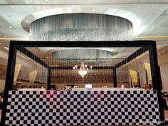 a checkered table in front of a chandelier with lights hanging from the ceiling