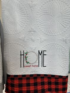 a close up of a quilt with the words home on it and a red checkered pillow