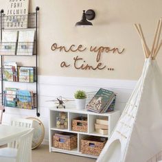 a teepee tent sitting next to a white shelf filled with books