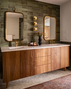 a bathroom vanity with two mirrors above it and a vase on the counter next to it