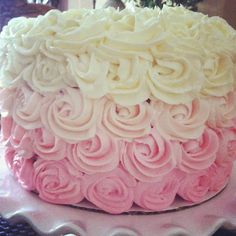 there is a cake with pink and white frosting on the top, sitting on a plate