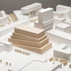 an architectural model of a city with lots of white buildings and trees in the background