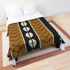 a bed with a brown and black blanket on top of it next to a white pillow