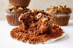 three cupcakes with chocolate frosting and nuts on top, one cut in half