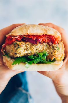 a hand holding a sandwich with meat and veggies on it in front of the camera