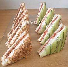 several sandwiches cut in half and stacked on top of each other with cucumber slices