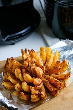 some fried food is sitting on a piece of tin foil next to an air fryer