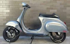 a silver scooter parked next to a brick wall