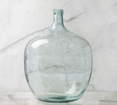 a clear glass bottle sitting on top of a marble counter next to a white wall