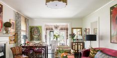 a living room filled with lots of furniture and paintings on the wall next to a fire place