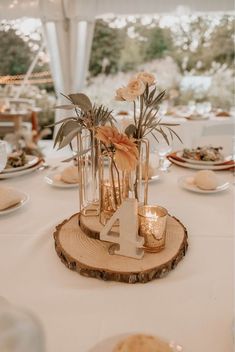 the table is set with candles, plates and flowers in glass vases on wood slices