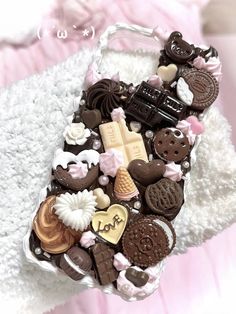 a cell phone covered in lots of different types of cookies and candies on top of a white blanket