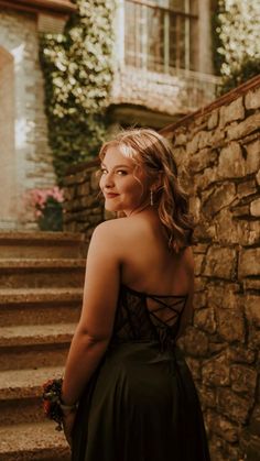 a woman in a black dress is standing on some steps and looking off into the distance