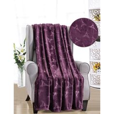 a purple blanket sitting on top of a chair next to a vase with flowers in it