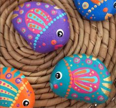 three painted rocks sitting on top of a wicker basket