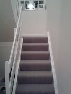 a set of stairs leading up to a window in a room with white walls and carpet