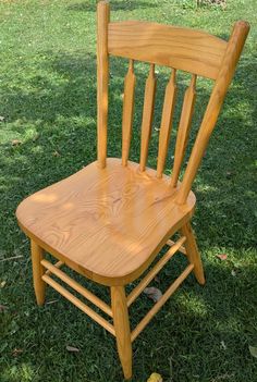 a wooden chair sitting on top of a lush green field