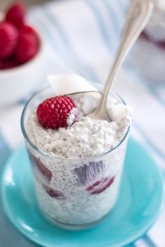 a bowl filled with yogurt and raspberries on top of a blue plate