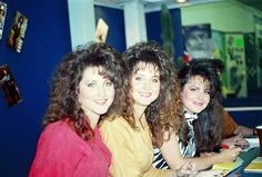 three women are sitting at a table smiling for the camera