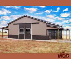 a large metal building sitting on top of a dry grass field