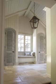 an empty room with shutters and a lantern hanging from the ceiling in front of two windows