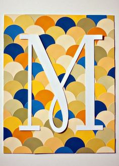 the letter m is made out of paper and sits in front of a wall decoration