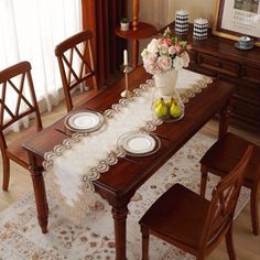 a dining room table set for four with plates and fruit on the placemats