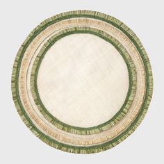 a round rug with green and beige trimmings on the bottom, in front of a white background