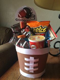 a cup filled with candy and snacks on top of a wooden table next to a lamp