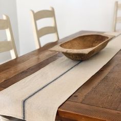 a wooden bowl sitting on top of a table next to a white cloth covered chair