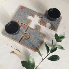 two mugs are sitting on the floor next to puzzle pieces