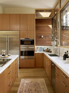 a kitchen with wooden cabinets and white counter tops, along with a rug on the floor