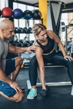 a man and woman doing squats in a gym