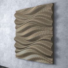 an abstract wall sculpture with wavy lines on the back and sides, mounted against a gray wall