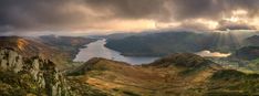 the sun shines through storm clouds over mountains and lakes on a cloudy day in scotland