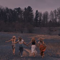 four girls running in a field holding hands