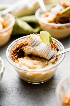 small bowls filled with dessert sitting on top of a table next to bananas and lime wedges