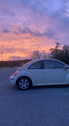 a white car parked in a parking lot at sunset