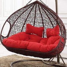 a hanging chair with red pillows on it