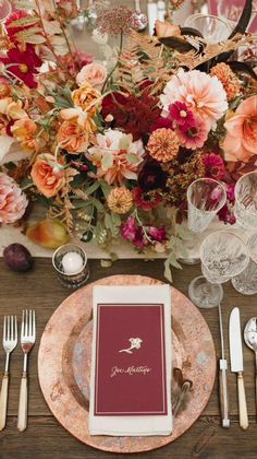 a table setting with place settings, silverware and flowers in the centerpieces