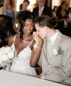 a bride and groom are sitting at a table with their hands on each other's cheek