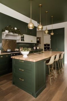 a large kitchen with green cabinets and wooden counter tops, gold pendant lights over the island