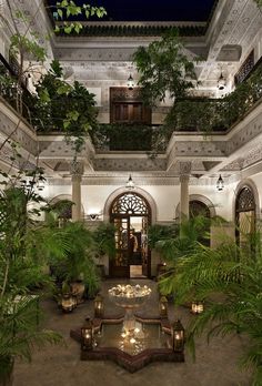 an indoor courtyard with potted plants and lights on the ceiling is lit up at night